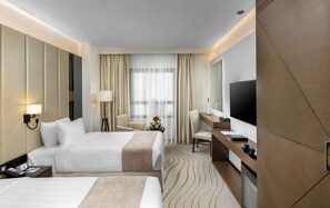 A hotel room with two beds, a desk, a chair, a TV, and a bathroom. - Jayden Hotel (Madinah)
