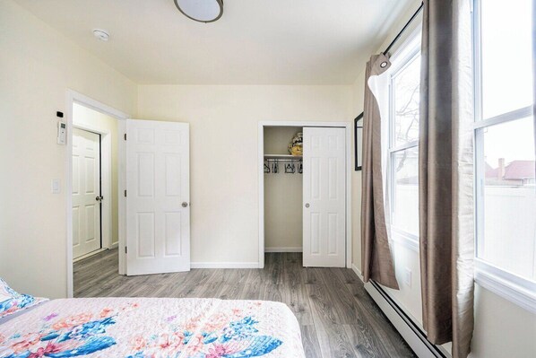 Un dormitorio con cama, armario y ventana con cortinas.