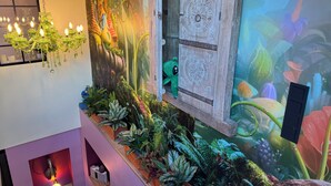 A room with a mural of a forest scene, a chandelier, and a window with a decorative wooden door. - Boutique Apartments by Roy GmbH  (Oberhausen)