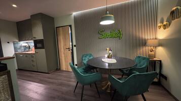 A modern kitchen with a dining area featuring teal chairs and a round table.
