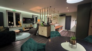 A modern living room with a flat-screen TV, comfortable seating, a dining table, and a staircase leading to an upper level. - Boutique Apartments by Roy GmbH  (Oberhausen)