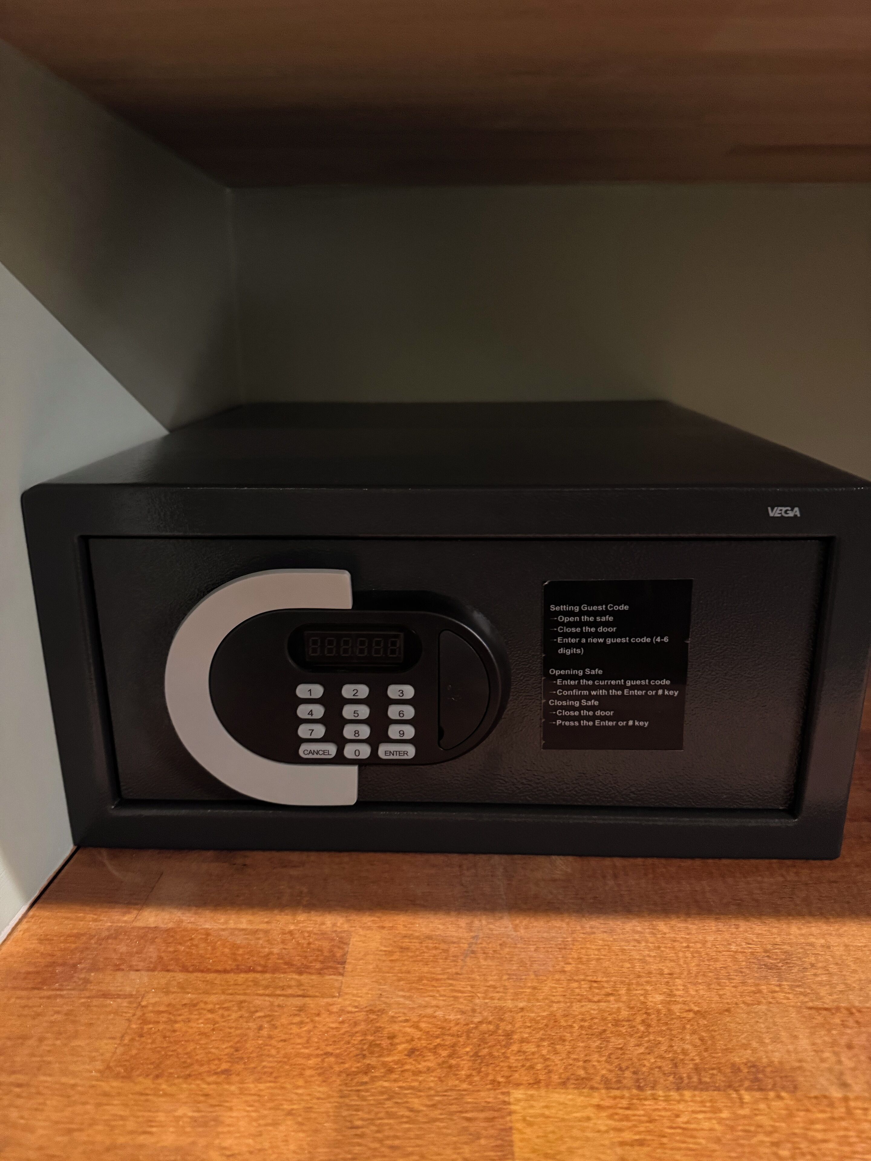 Een zwarte magnetron met een digitaal keypad en een sticker met instructies voor de gastcode.