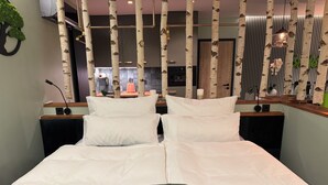 A double bed with white linens, a green textured bedspread, and a wall-mounted TV. - Boutique Apartments by Roy GmbH  (Oberhausen)