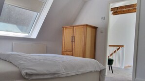 Un dormitorio con cama, un armario de madera, un tragaluz y vista a una escalera.