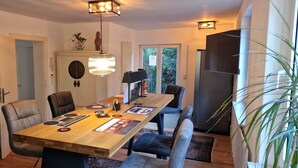 Un comedor con una mesa de madera, sillas, una lámpara colgante y vistas al exterior.
