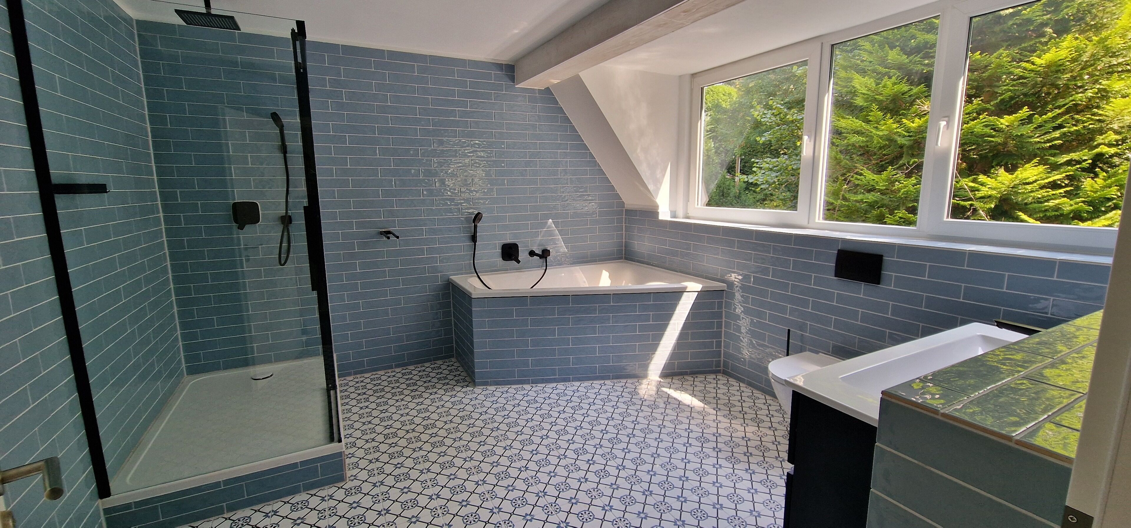 Une salle de bain dotée d’une douche à parois de verre, d’une baignoire sur pieds et d’une fenêtre donnant sur un paysage verdoyant.