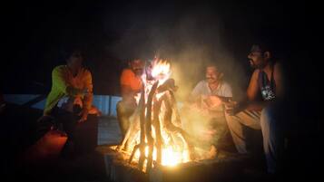 A group of people sitting around a campfire at night.