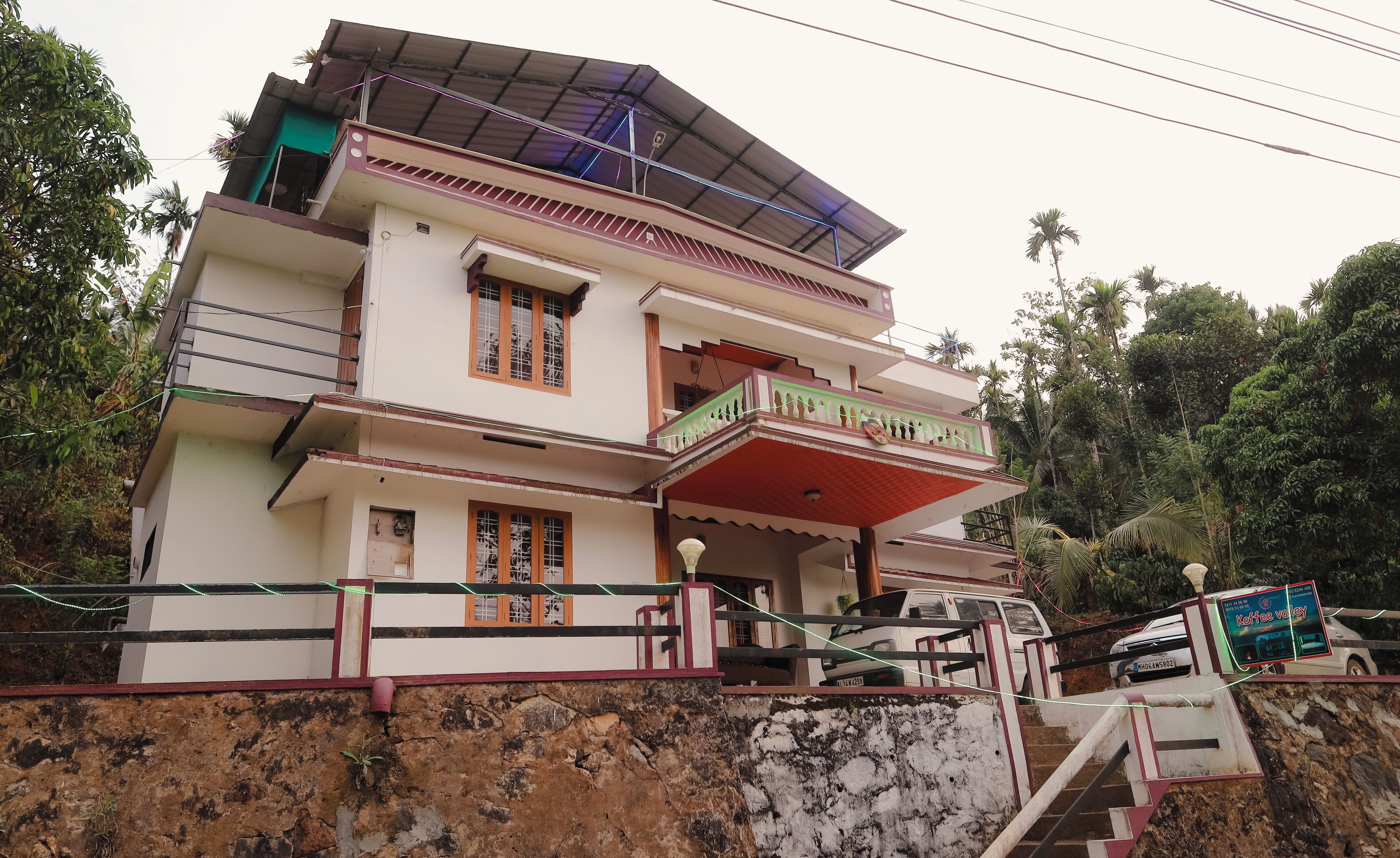 A multi-story house with a balcony, a staircase, and a parked vehicle.