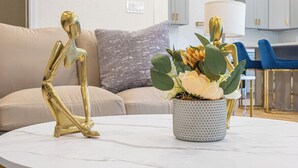 A modern living room with a round marble table, a gold abstract sculpture, and a vase of flowers. - Stunning Elegance 4br/2.5 BA Near Vibrant Downtown (San Antonio)