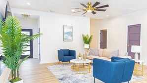 A modern living room with a sofa, two armchairs, a coffee table, and a ceiling fan. - Stunning Elegance 4br/2.5 BA Near Vibrant Downtown (San Antonio)