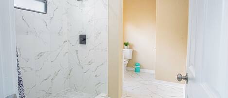 A bathroom with a shower, toilet, and sink.