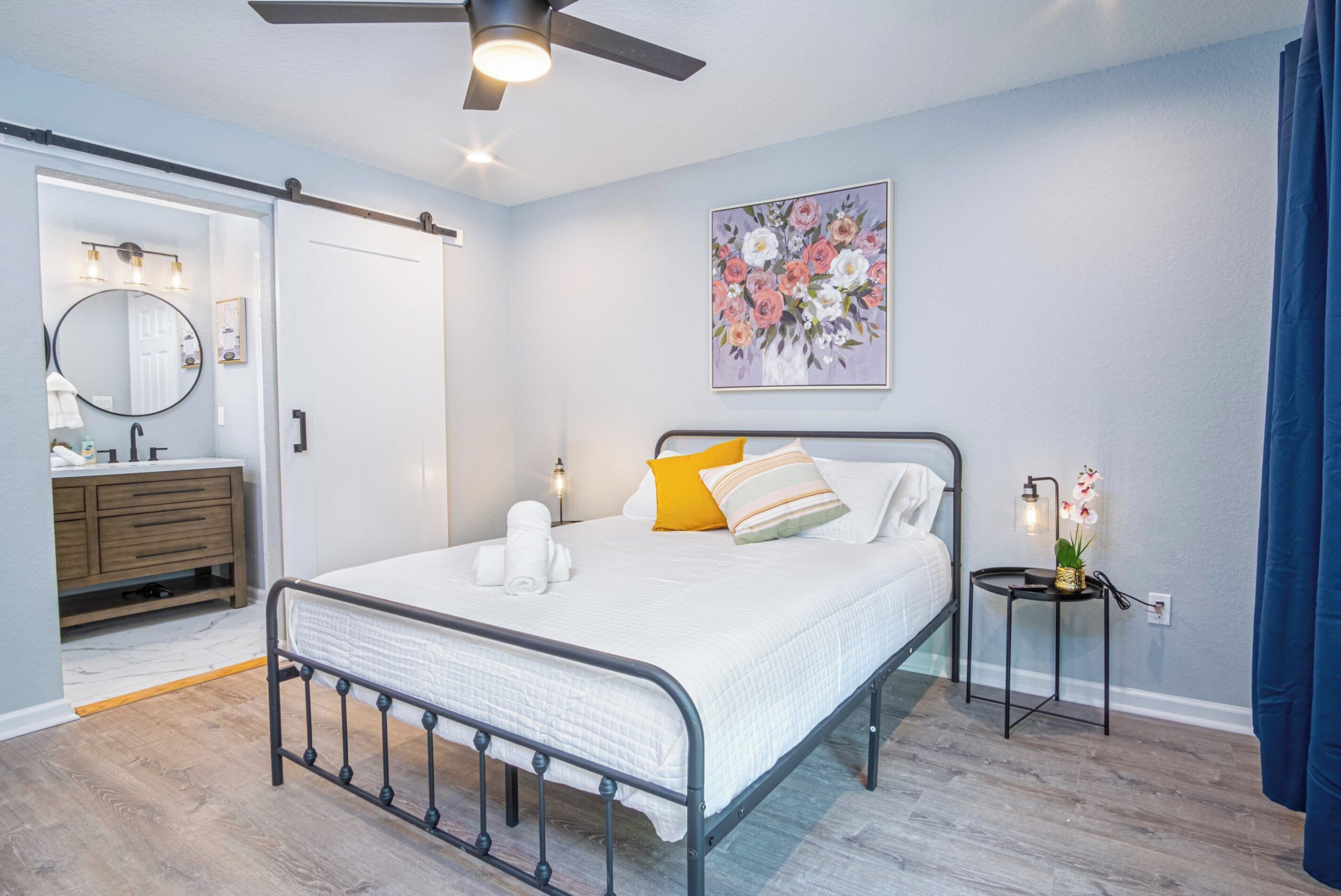 A neatly arranged bedroom with a bed, bedside table, and a ceiling fan.