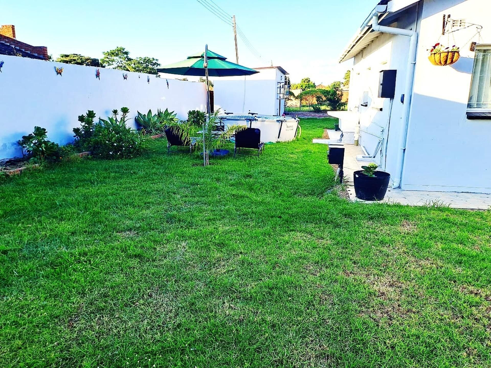 A well-maintained grassy yard with a pathway leading to a white building.