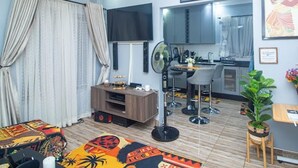 A modern living room with a TV, a dining area, and a kitchen. - 2bed-4guests-garden-nearcentre&attractions (Harare)