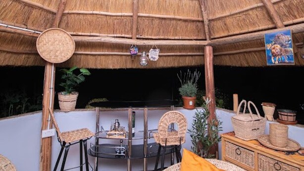 A thatched-roof structure with wicker furniture, a small table, and potted plants. - 2bed-4guests-garden-nearcentre&attractions (Harare)