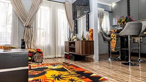 A modern living room with a sofa, a coffee table, a TV, and a patterned rug. - 2bed-4guests-garden-nearcentre&attractions (Harare)