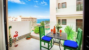 Un balcon avec une table et des chaises, une vue sur la mer et une statue de flamant décorative.