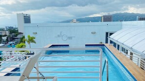 A rooftop pool area with a view of the cityscape, including buildings and mountains in the distance. - Island vibes Oasis with a beautiful Pool (Kingston)