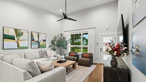 A modern living room with a sofa, chairs, a coffee table, and a TV.