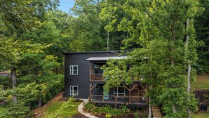 A modern two-story house surrounded by dense forest.