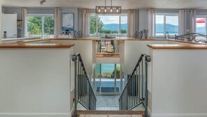 A modern kitchen with a central island, a dining area with chairs, and a view of the outdoors. - Stunning Lake Home w/ Private Dock, Spa, Fire Pit (Huddleston)
