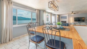 A modern kitchen with a wooden island, bar stools, and a view of the lake. - Stunning Lake Home w/ Private Dock, Spa, Fire Pit (Huddleston)