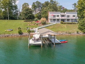Une propriété au bord du lac, dotée d’un quai, d’un espace salon couvert et d’un bâtiment à deux étages avec un balcon.