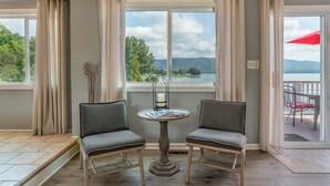 A room with two chairs, a table, and a view of a lake and mountains. - Stunning Lake Home w/ Private Dock, Spa, Fire Pit (Huddleston)