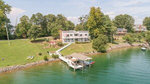 A lakeside property with a dock, a house, and a boat. - Stunning Lake Home w/ Private Dock, Spa, Fire Pit (Huddleston)