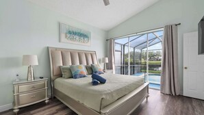 Ein Schlafzimmer mit einem großen Bett, einem Nachttisch, einer Lampe und Blick auf einen Swimmingpool durch eine Glastür.