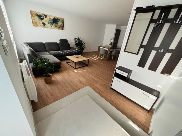 A modern living room with a sofa, coffee table, and a dining area with chairs.