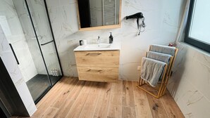Une salle de bain moderne avec un meuble-lavabo en bois, une cabine de douche en verre et un porte-serviettes.