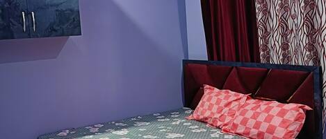 A bedroom with a bed, a wardrobe, and a curtain.