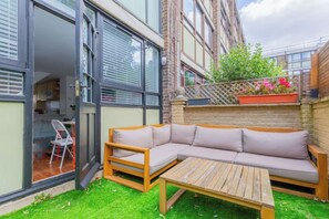Un espace extérieur moderne, aménagé avec une table en bois et un canapé rembourré.