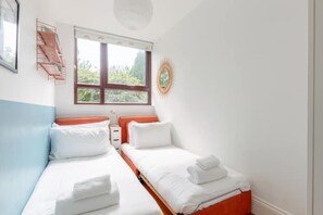 A room with two beds, a window, a wall-mounted shelf, and a ceiling light. - Unique 3BD Flat in Hoxton with Private Garden (Greater London)