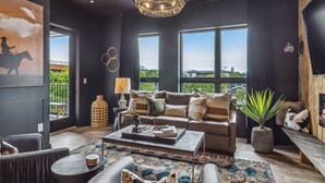 Un salon moderne avec une grande fenêtre, un lustre et un canapé.