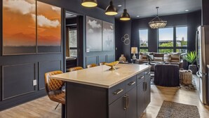 Une cuisine moderne dotée d’un îlot central, de luminaires suspendus et donnant sur l’espace de vie.