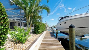 Une jetée en bois mène à une marina où est amarré un yacht blanc.