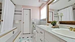 Une salle de bain avec deux lavabos, une baignoire, des toilettes et un espace douche.