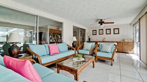 Un salon spacieux comprenant un grand canapé, deux fauteuils, une table basse et un ventilateur de plafond.