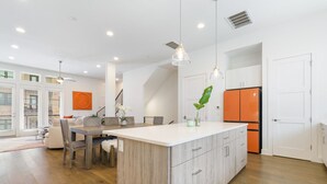 A modern kitchen with a central island, white cabinetry, and an orange refrigerator.