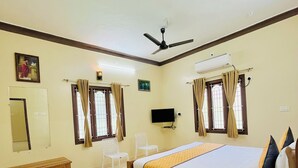 A hotel room with a bed, a TV, a ceiling fan, and an air conditioning unit. - SSS Golden Resorts (Tarangambadi)