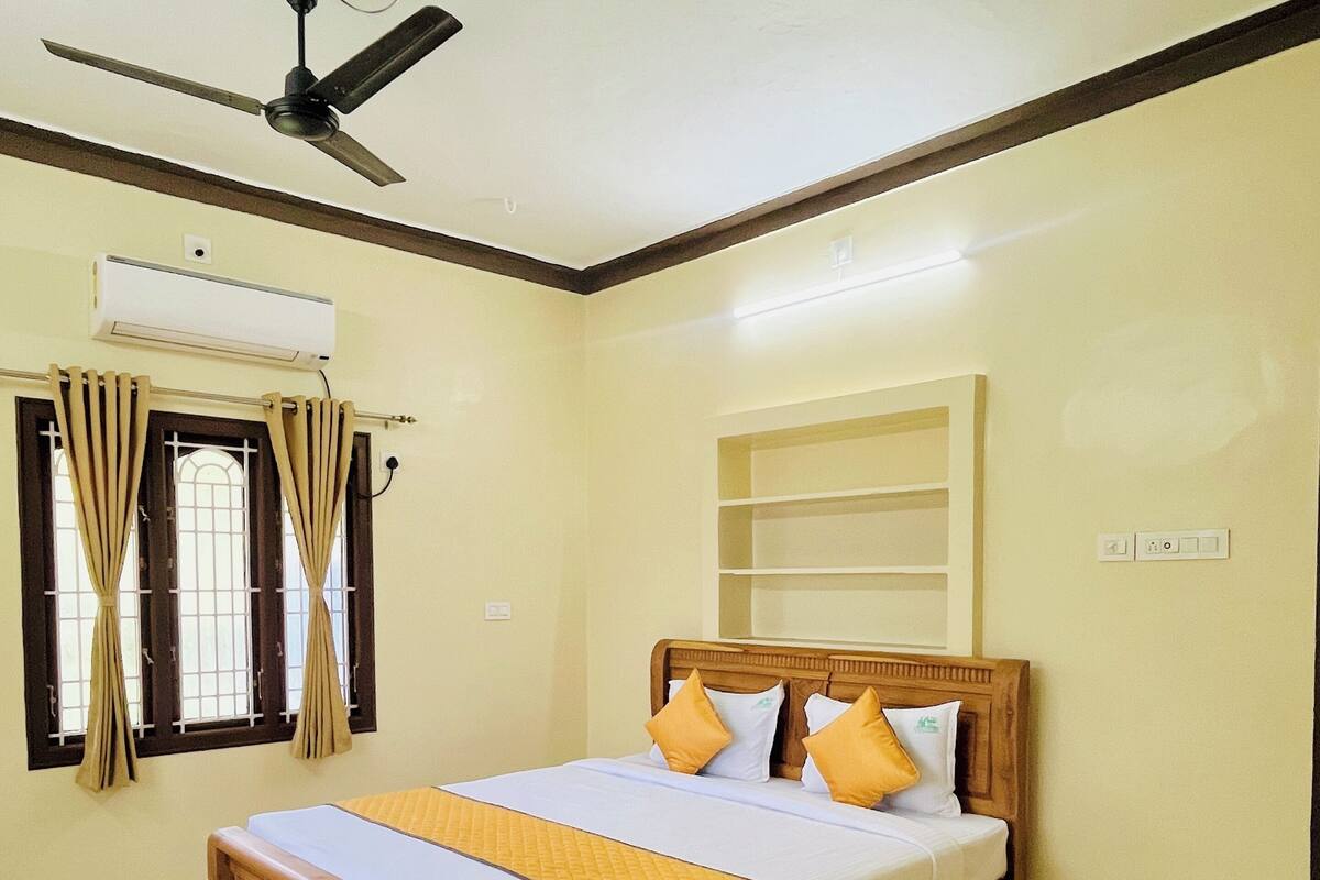 Ein Schlafzimmer mit einem hölzernen Bett, beige farbenen Wänden, einem Deckenventilator und einer Klimaanlage.