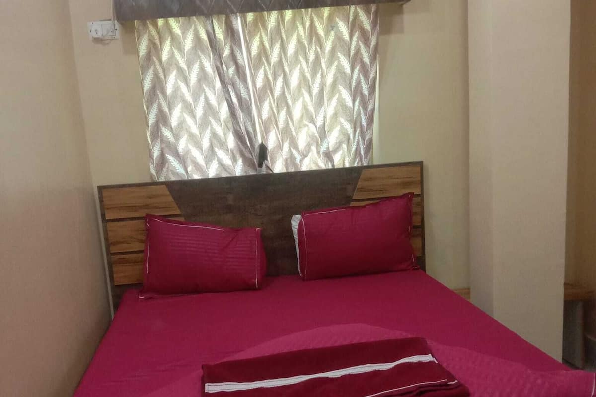 A bed with a wooden headboard, two red pillows, and a red bedspread.