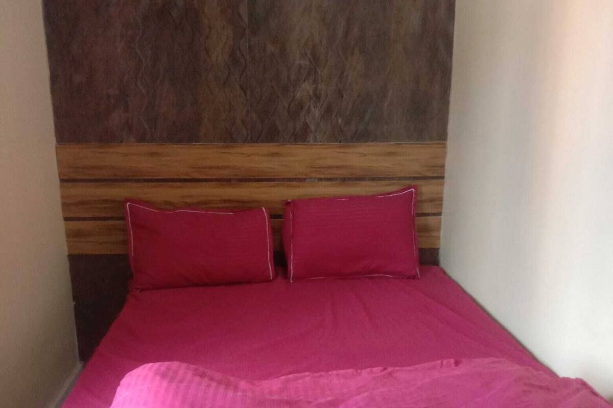 A bed with a wooden headboard and two pillows.