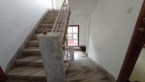 Eine Treppe mit Marmorstufen und einem Metallgeländer, die zu einer Tür mit rotem Rahmen führt.