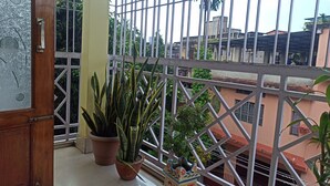 Ein Balkon mit Metallgeländer, Blumentöpfen und Blick auf Gebäude im Hintergrund.