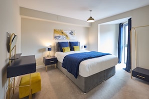 A modern bedroom with a large bed, bedside tables, a desk, and a wardrobe. - Host Stay The Hideaway (York)