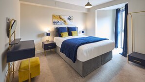 Une chambre moderne avec un grand lit, des tables de chevet, un bureau et une armoire.
