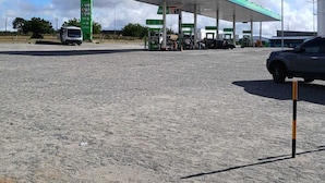 A gas station with a green canopy, a fuel price sign, and a few vehicles parked. - Hotel Prime Suítes (Cupira)